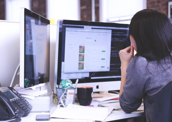 Office worker looking at computer screens, considering the budget